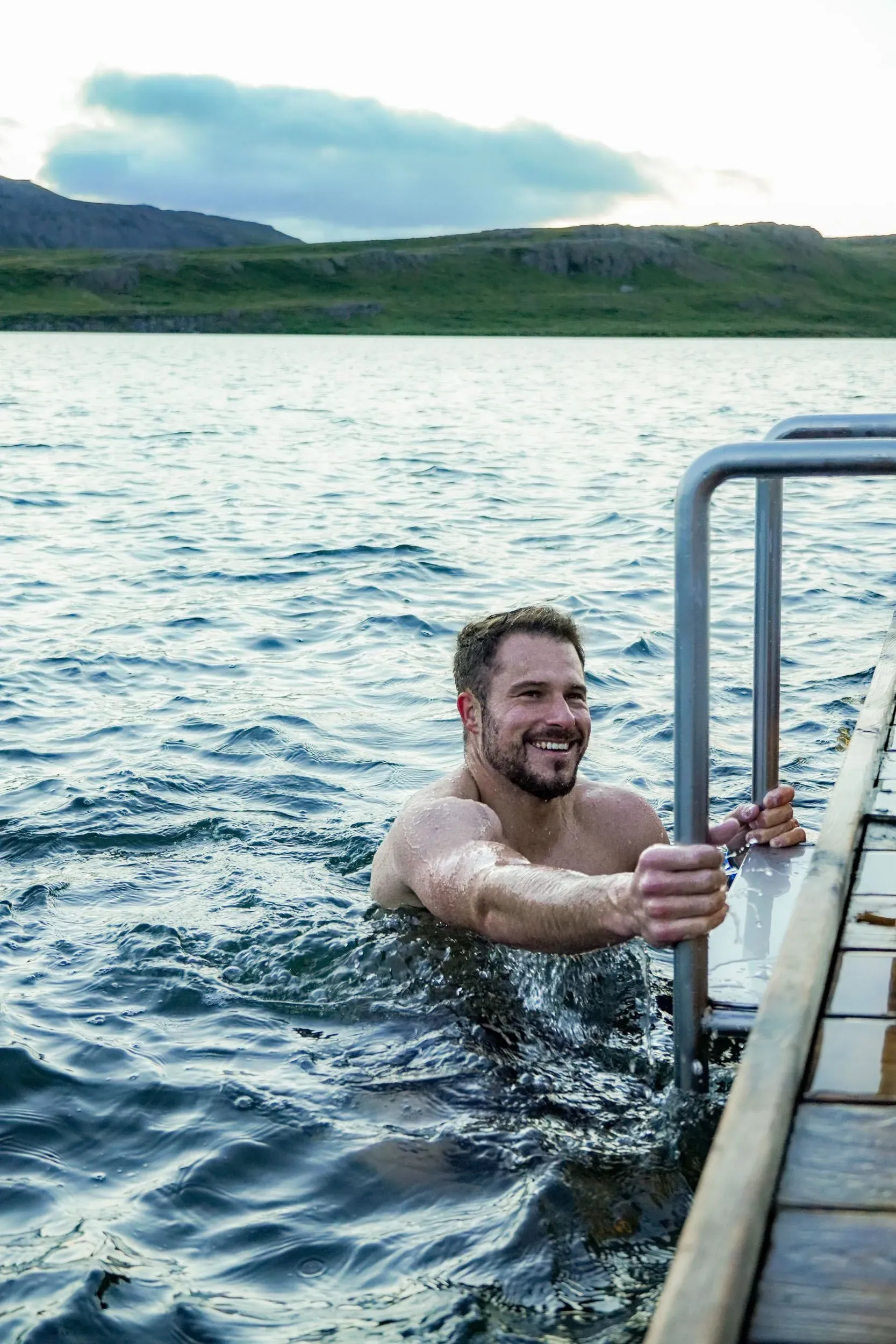 A swimmer climbing down the ladder from a floating pool into the lake