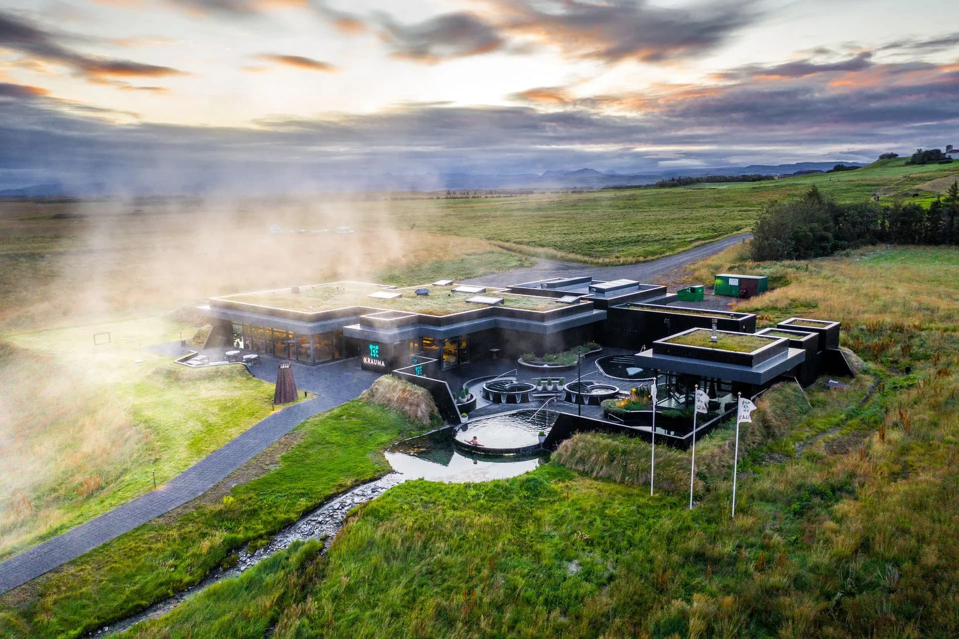 Aerial view of Krauma’s dark, turf-roofed buildings with steam rising from the pools