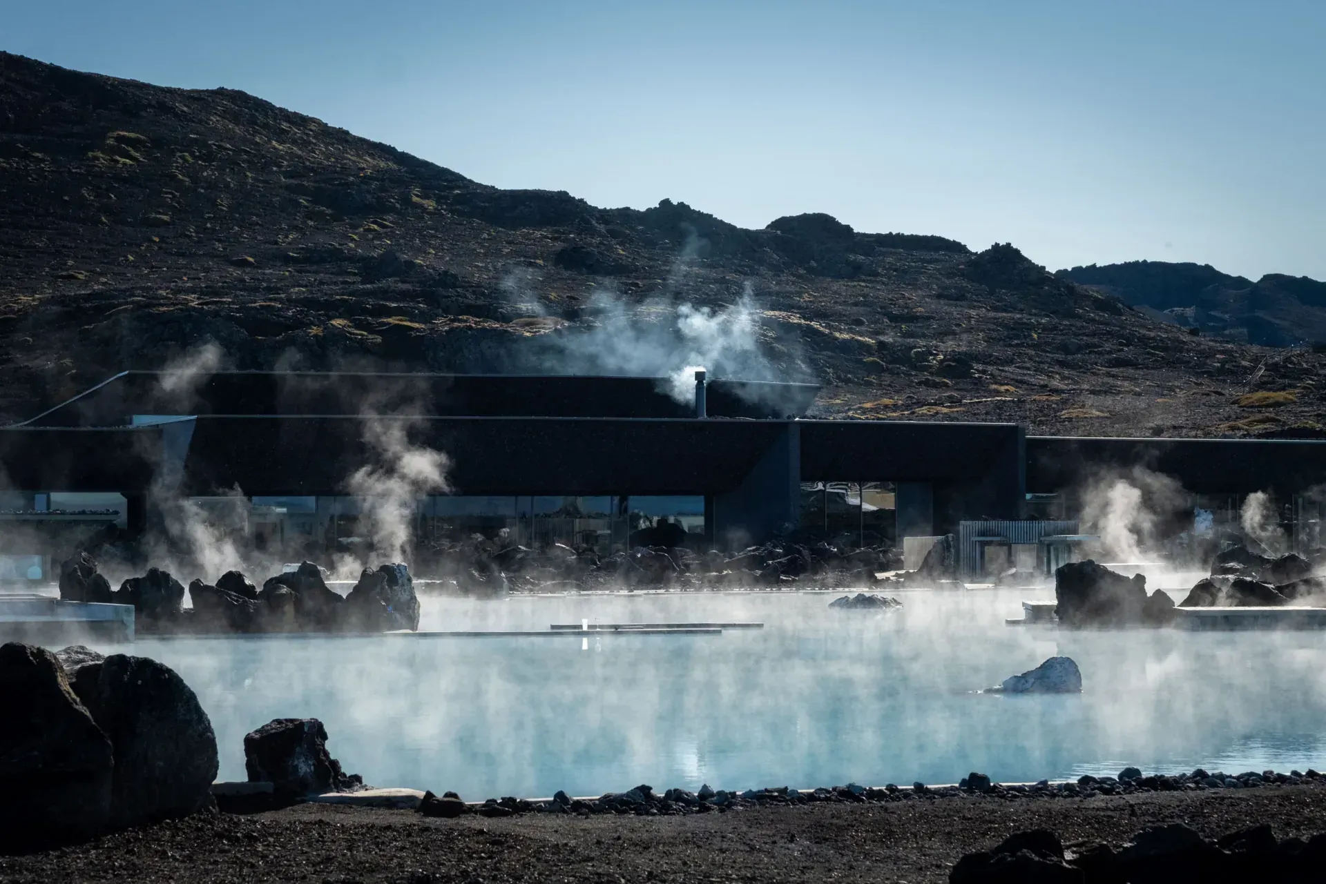Steam rising off the lagoon below a dark ridge