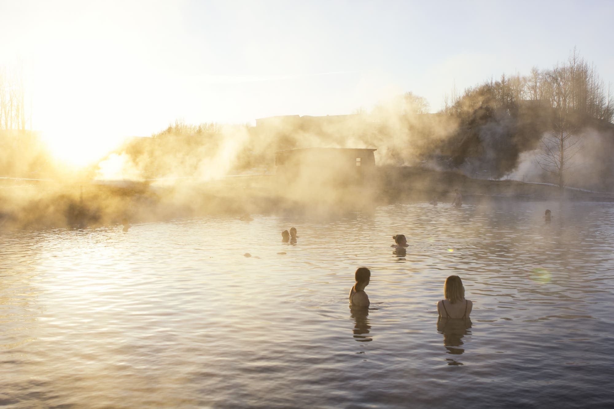 Bathers in the misty Secret Lagoon in soft golden backlight