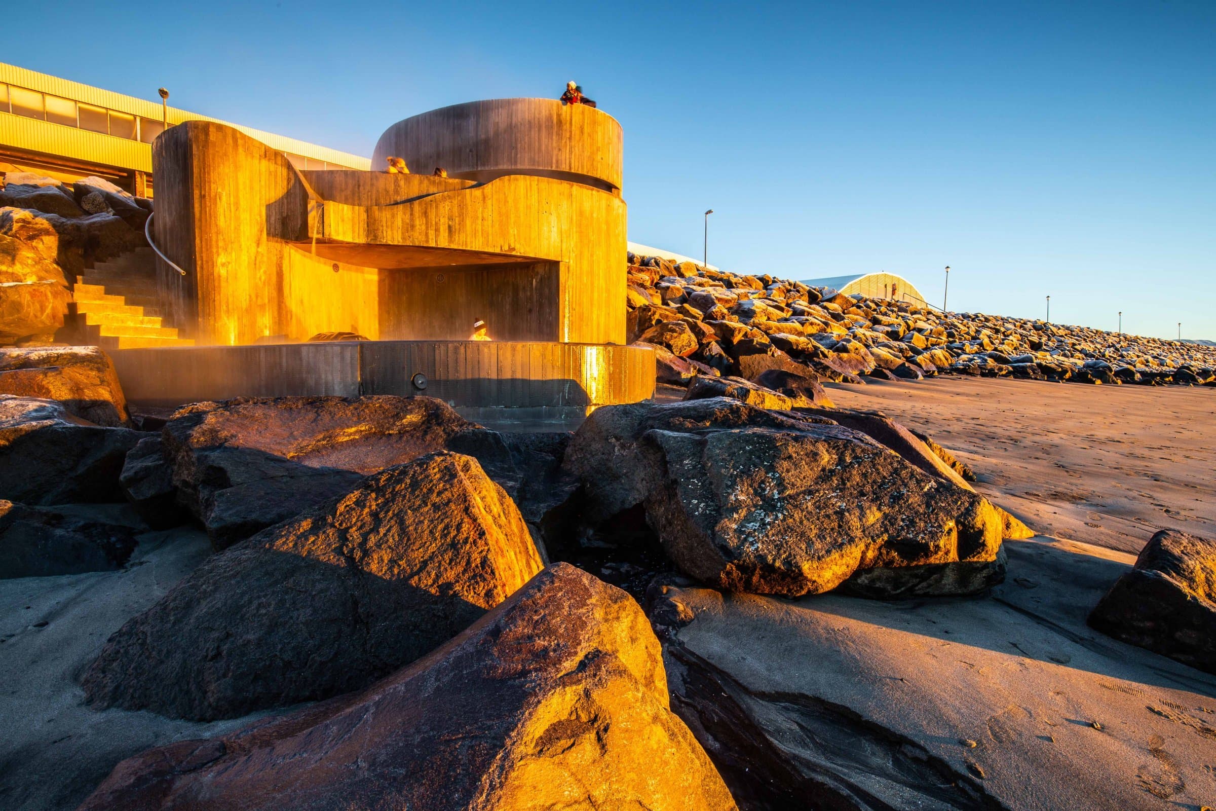 Guðlaug’s concrete tiers rising from the stone breakwater at Langisandur