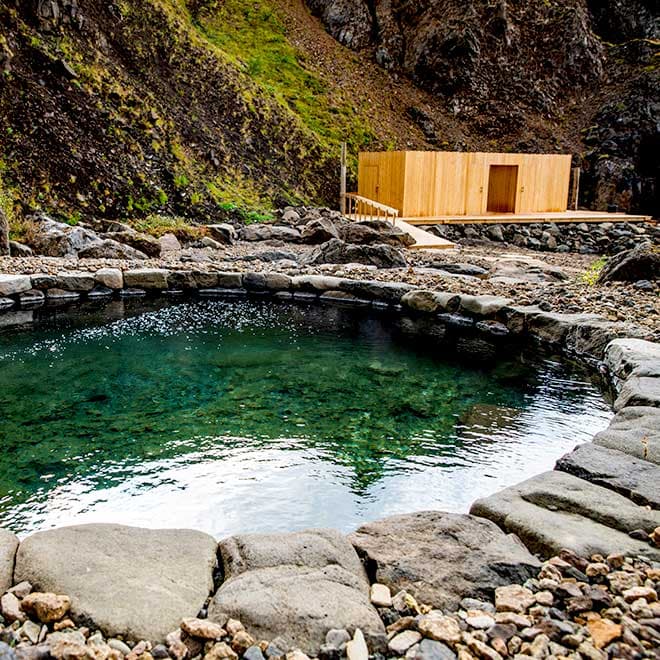 An emerald, stone-rimmed pool with the bathhouse behind