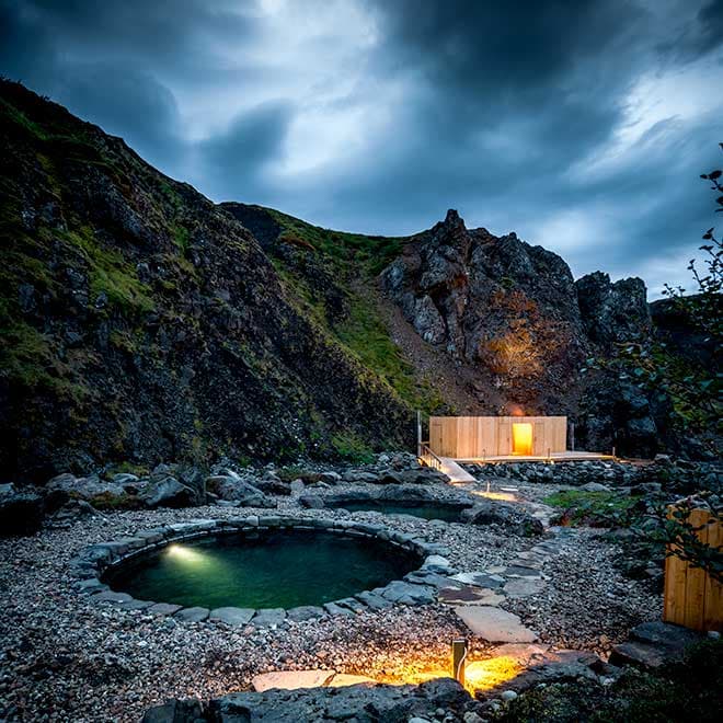 The glowing bathhouse at twilight against the canyon wall