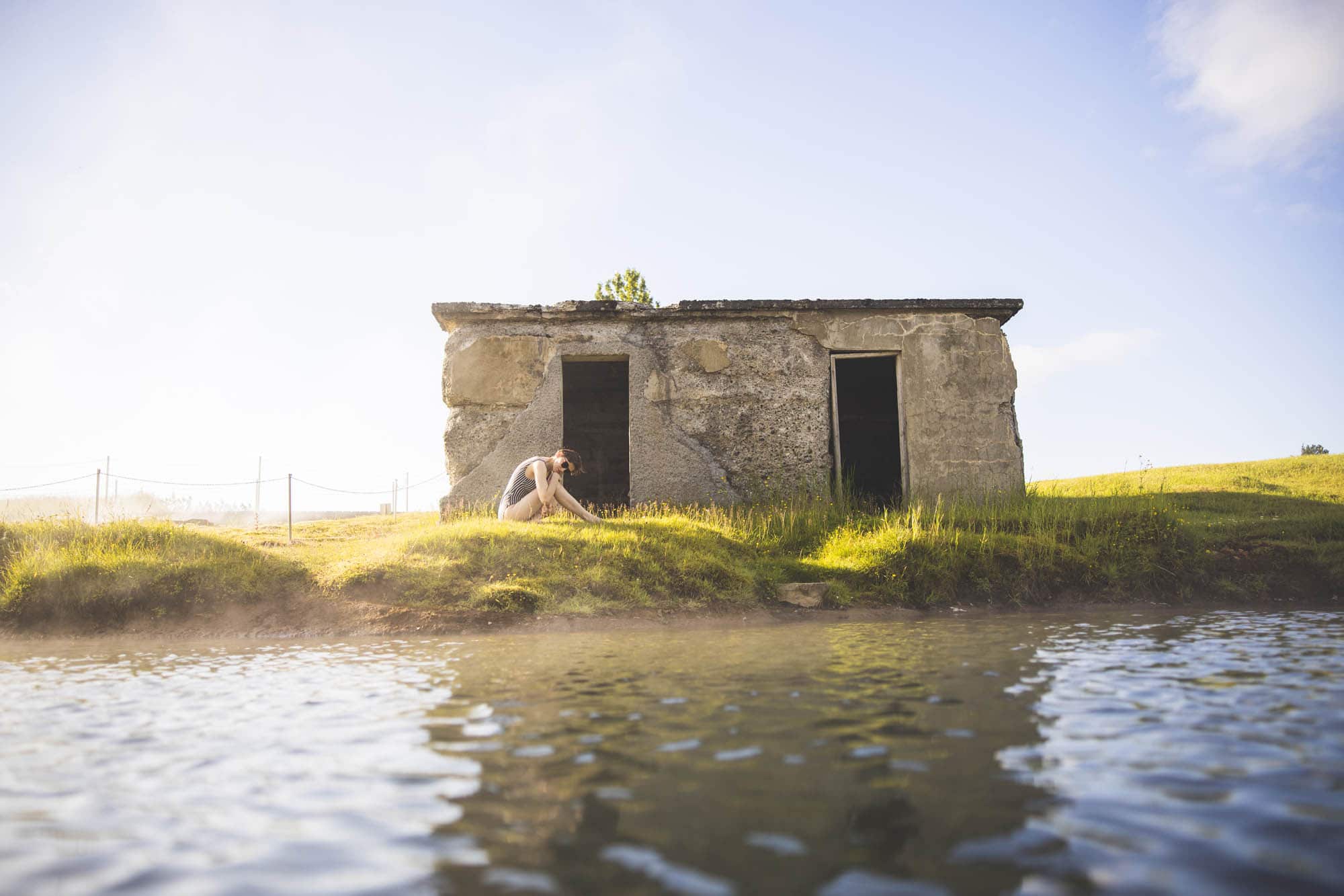The weathered stone hut on the lagoon’s grassy edge in low sun