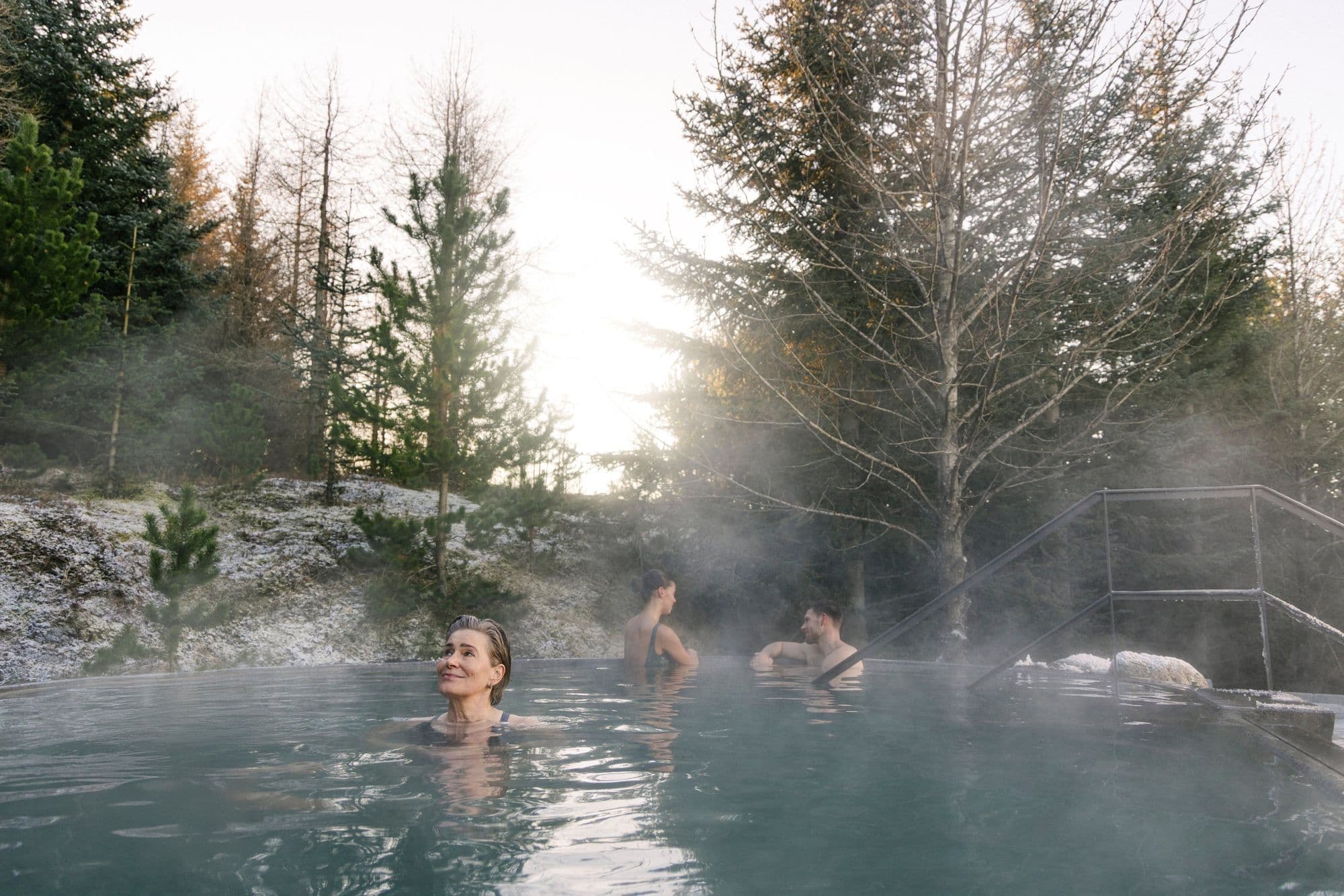 Bathers in the forest pool among snow-dusted spruce trees